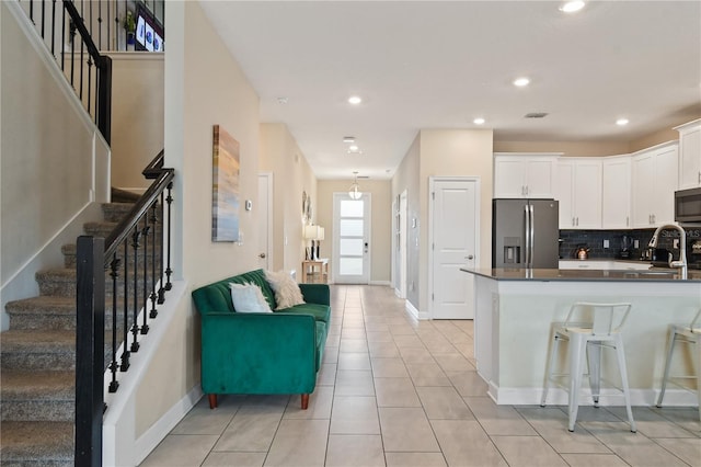 kitchen with kitchen peninsula, appliances with stainless steel finishes, backsplash, light tile patterned floors, and white cabinets