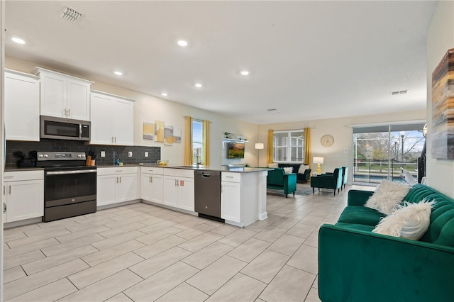 8834 Cabot Cliffs Dr, Davenport, FL 33896 - kitchen with dishwashing machine, range with electric stovetop, stainless steel microwave, open floor plan, and a peninsula