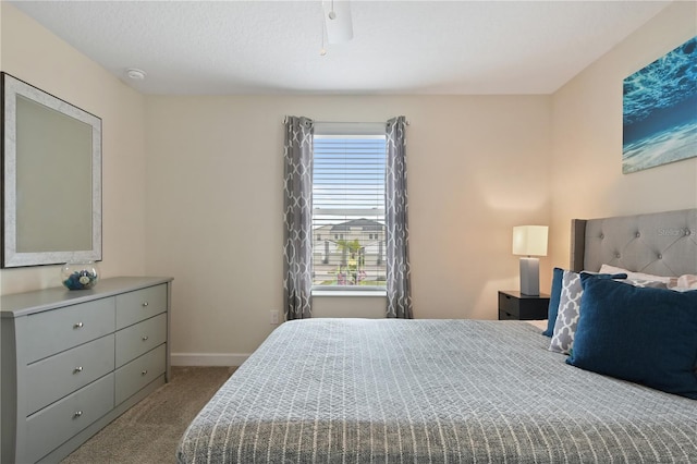 bedroom featuring ceiling fan, light colored carpet, and a textured ceiling