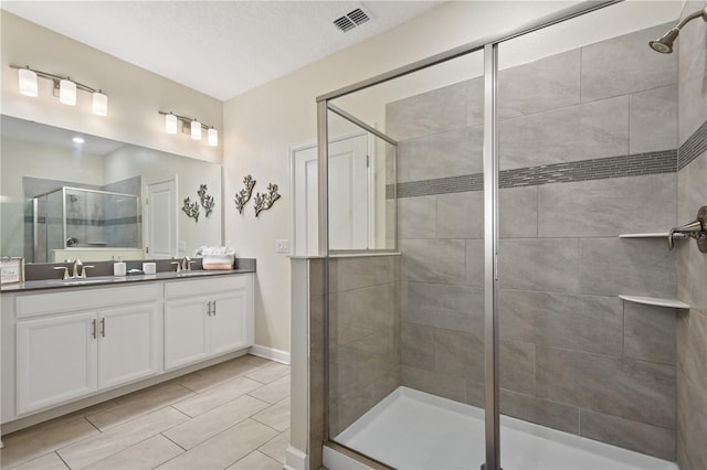 bathroom featuring a textured ceiling, vanity, and a shower with door