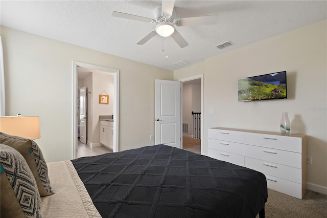 bedroom featuring light carpet, a textured ceiling, connected bathroom, and ceiling fan