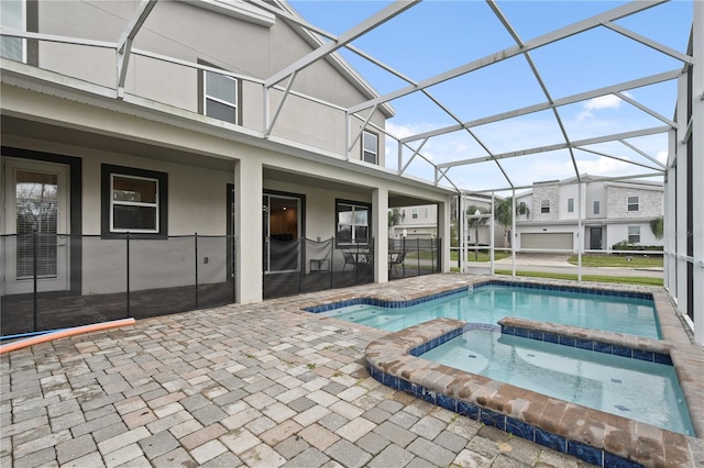 view of pool featuring glass enclosure, an in ground hot tub, and a patio area