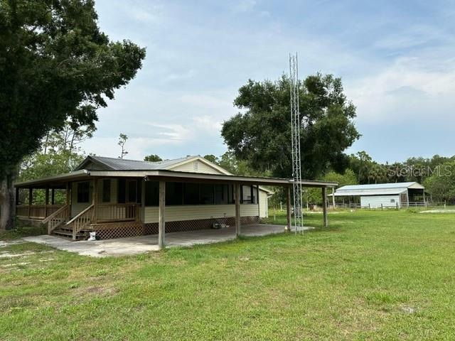 rear view of house featuring a carport and a yard