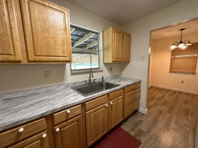 kitchen with a chandelier, sink, dark wood-type flooring, and hanging light fixtures