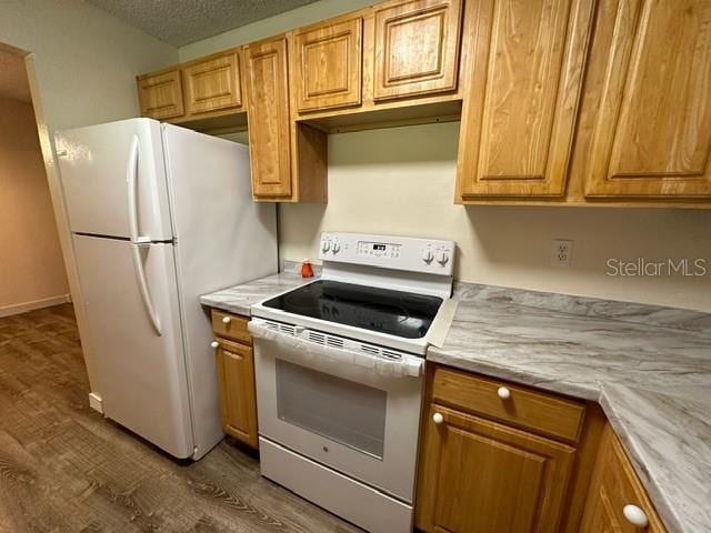 kitchen with a textured ceiling, white appliances, and dark hardwood / wood-style floors