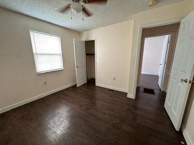 unfurnished bedroom featuring ceiling fan, a textured ceiling, and dark wood-type flooring