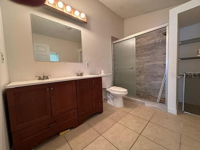 bathroom with dual vanity, walk in shower, toilet, and tile floors