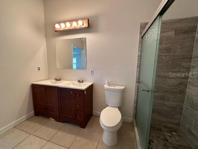 bathroom with a shower with door, toilet, tile floors, and large vanity