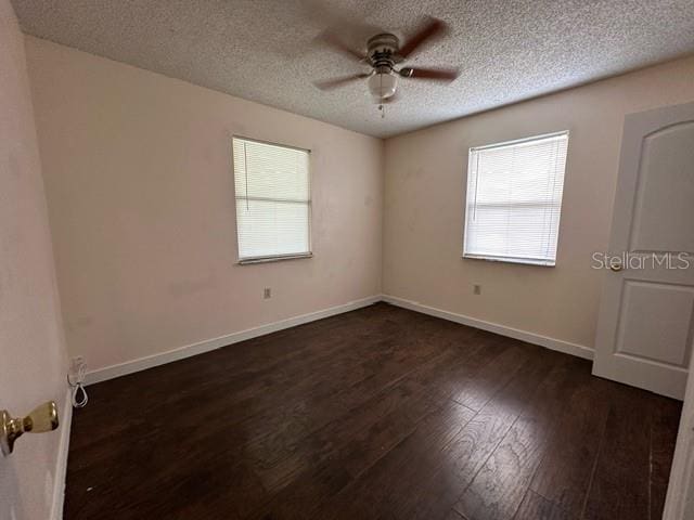 empty room featuring a textured ceiling, dark hardwood / wood-style floors, and ceiling fan