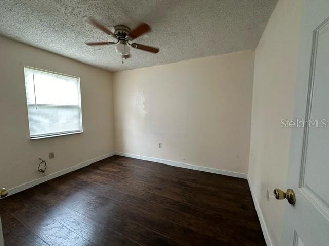 spare room with a textured ceiling, ceiling fan, and dark hardwood / wood-style flooring