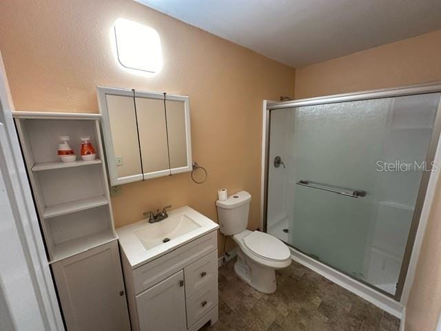 bathroom featuring an enclosed shower, vanity, toilet, and tile floors