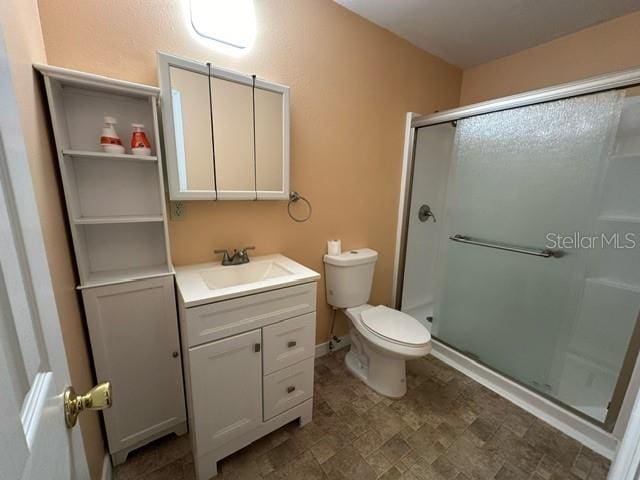 bathroom featuring a shower with shower door, vanity, toilet, and tile floors