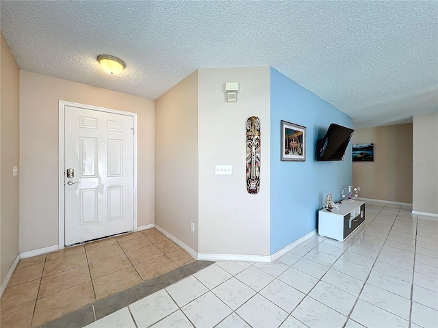 foyer entrance with a textured ceiling and light tile patterned floors