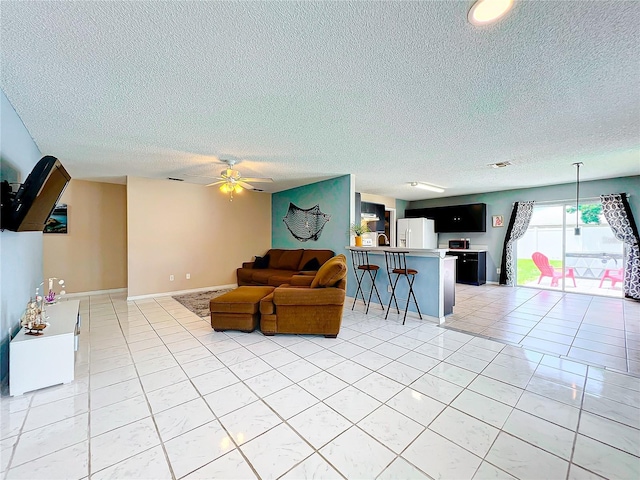 tiled living room featuring a textured ceiling and ceiling fan