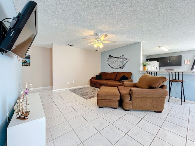 living room featuring light tile patterned floors, a textured ceiling, and ceiling fan