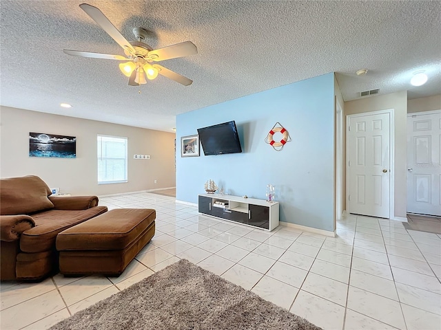 living room with ceiling fan, a textured ceiling, and light tile patterned floors