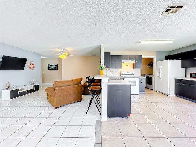 kitchen with light tile patterned flooring, sink, a kitchen breakfast bar, kitchen peninsula, and white appliances