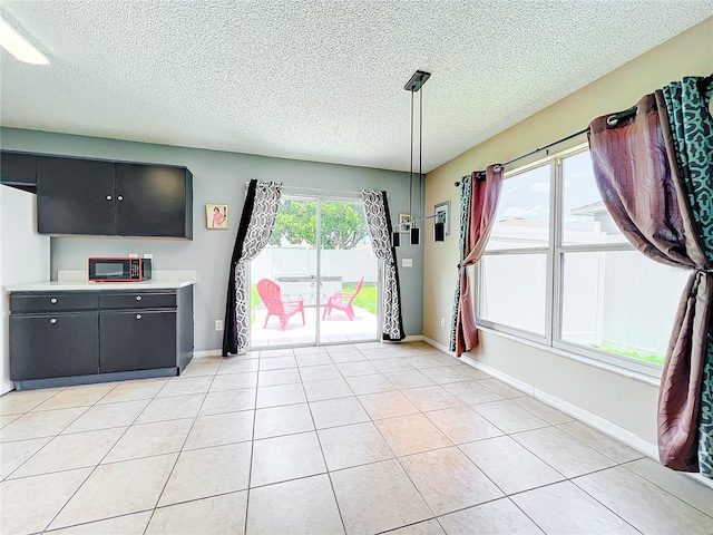 unfurnished dining area featuring a healthy amount of sunlight, light tile patterned floors, and a textured ceiling