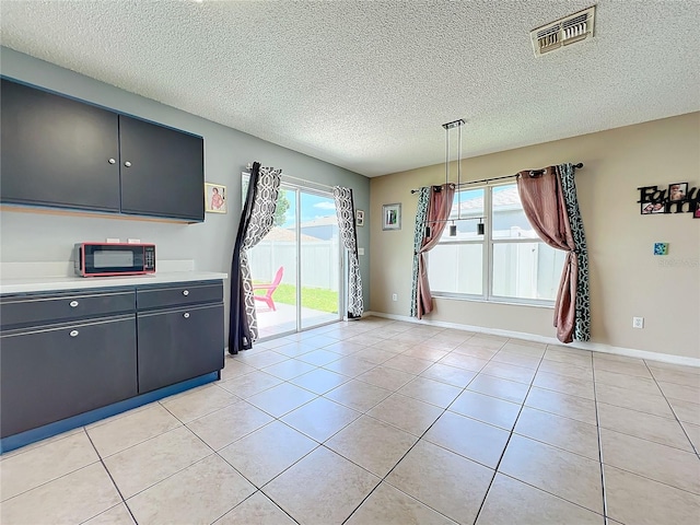 unfurnished dining area featuring a textured ceiling, a healthy amount of sunlight, and light tile patterned flooring