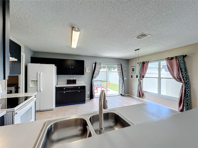 kitchen featuring white appliances, decorative light fixtures, sink, and light tile patterned floors