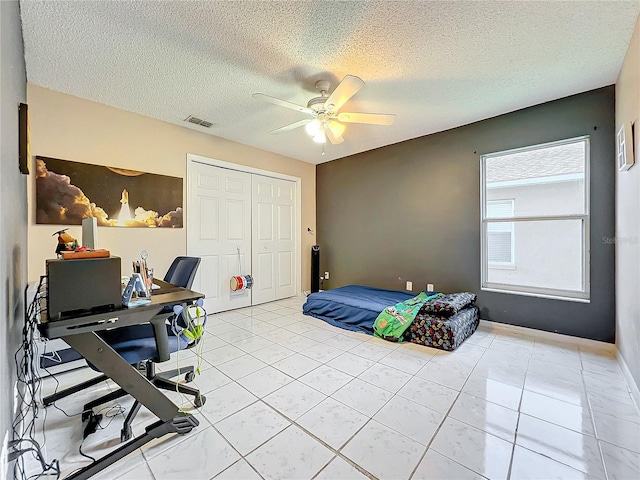 bedroom with a textured ceiling, ceiling fan, and a closet