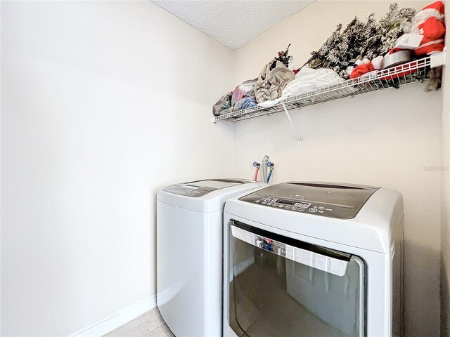 washroom with separate washer and dryer, a textured ceiling, and light tile patterned flooring