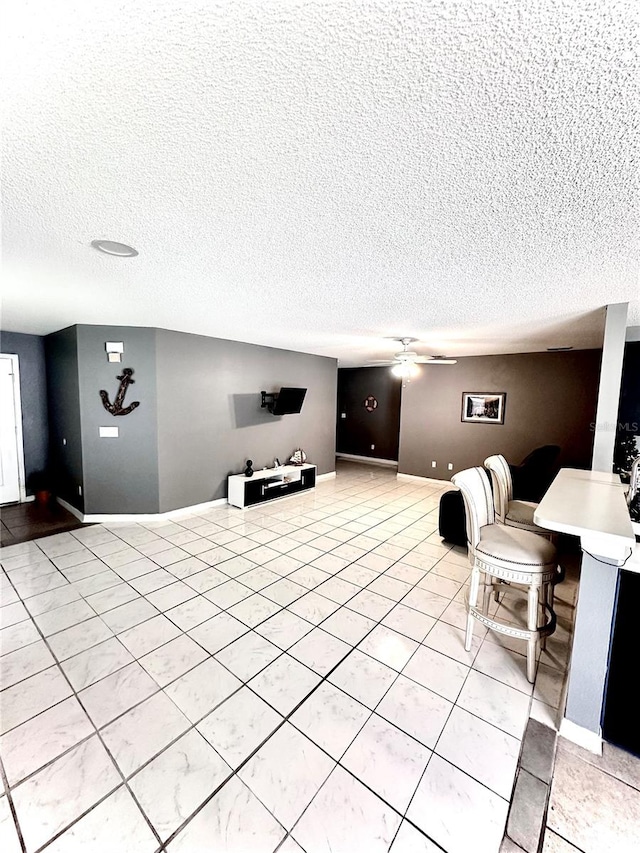 unfurnished living room featuring a textured ceiling, ceiling fan, and light tile patterned flooring