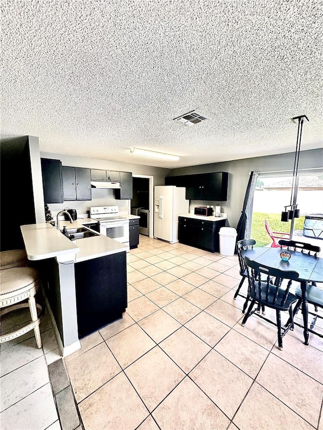 kitchen featuring a kitchen bar, sink, decorative light fixtures, kitchen peninsula, and white appliances