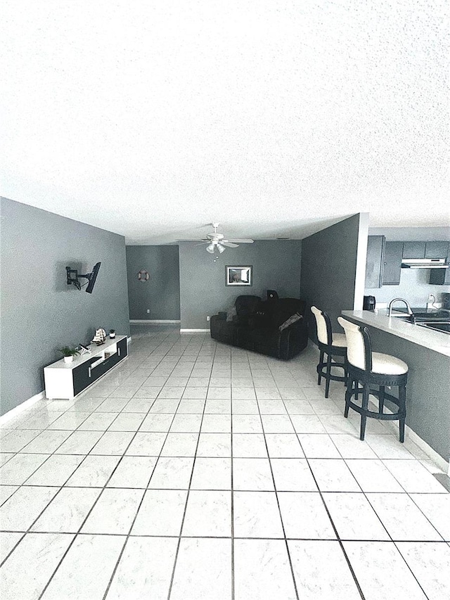 tiled living room featuring ceiling fan and a textured ceiling