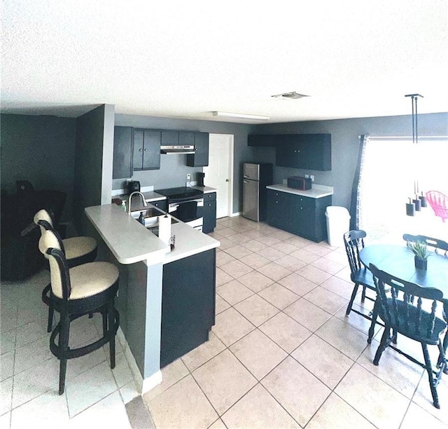 kitchen featuring pendant lighting, a breakfast bar, fridge, stainless steel range with electric cooktop, and kitchen peninsula