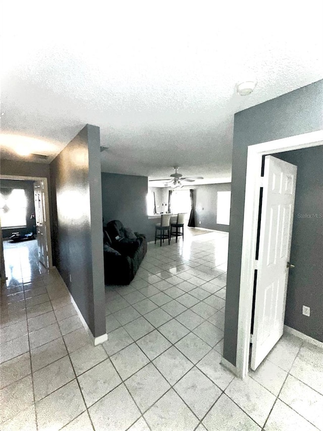 corridor featuring light tile patterned flooring and a textured ceiling