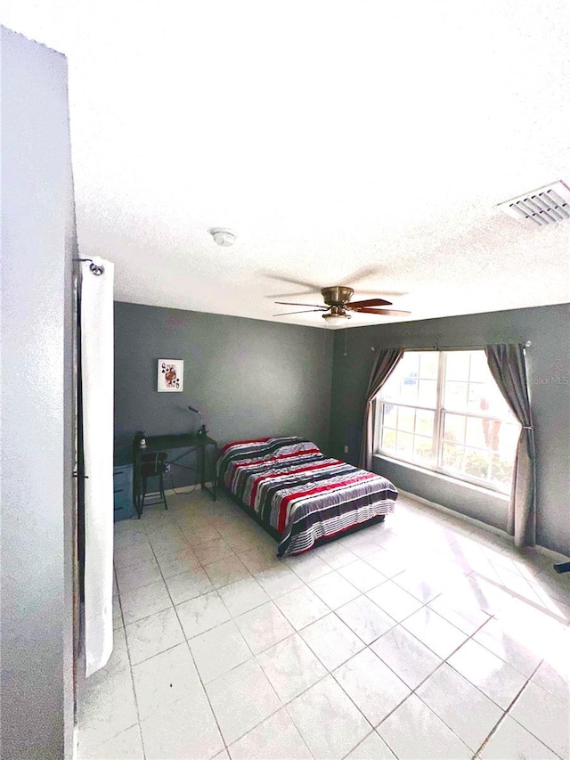 bedroom with ceiling fan, a textured ceiling, and light tile patterned floors