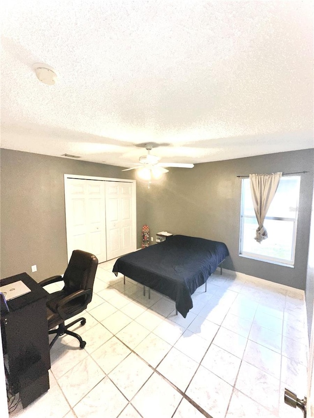 tiled bedroom featuring a textured ceiling, a closet, and ceiling fan