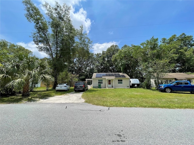 view of front of property with a front yard and solar panels