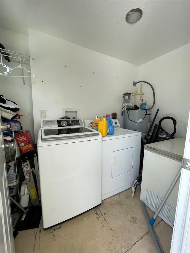 washroom featuring water heater, washing machine and dryer, and hookup for a washing machine