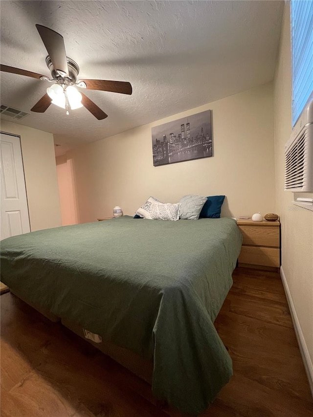 bedroom featuring ceiling fan, a textured ceiling, and dark wood-type flooring