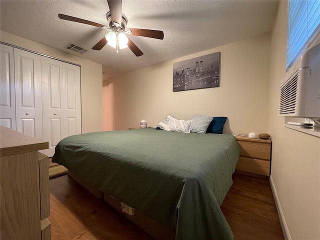 bedroom featuring dark hardwood / wood-style floors, ceiling fan, a closet, and a textured ceiling