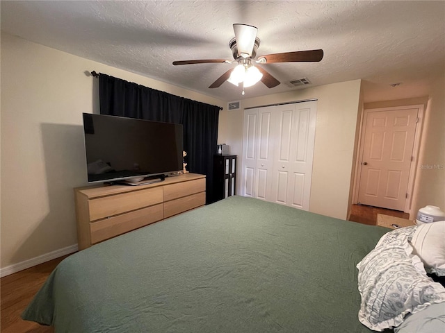 bedroom featuring a textured ceiling, dark wood-type flooring, a closet, and ceiling fan