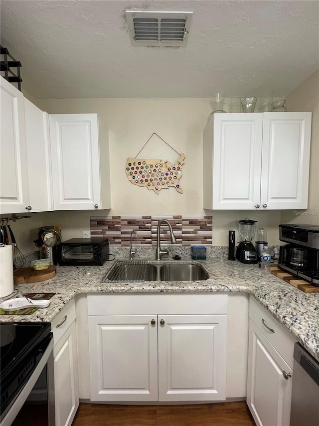 kitchen with dishwasher, stove, sink, white cabinets, and hardwood / wood-style flooring