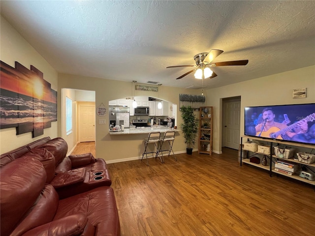 living room with hardwood / wood-style floors, ceiling fan, and a textured ceiling