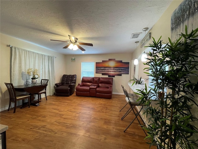 living room featuring a textured ceiling, ceiling fan, and hardwood / wood-style floors