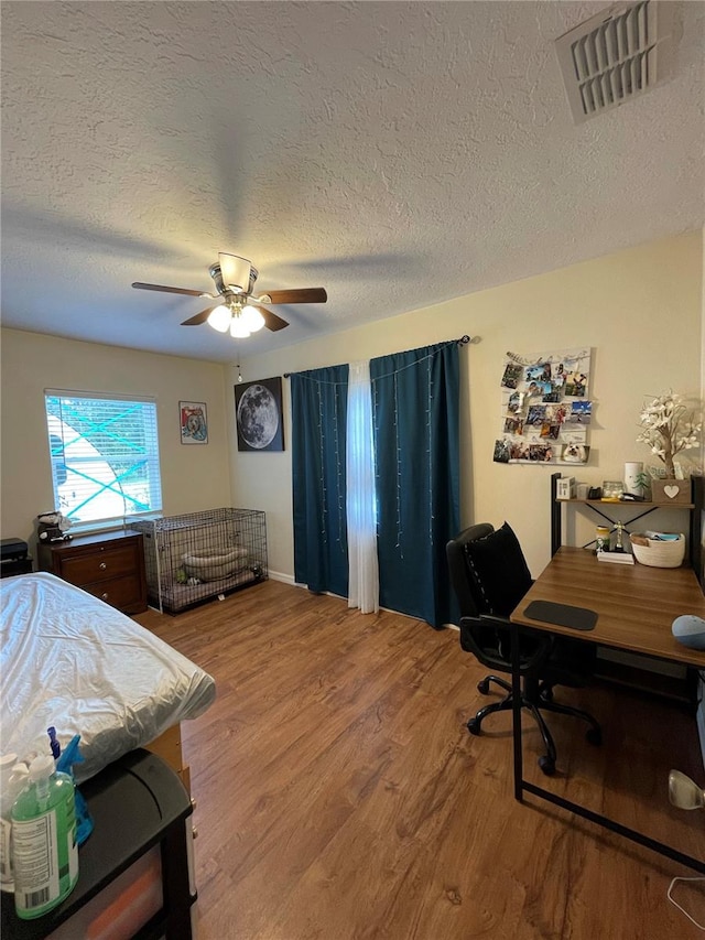 bedroom with ceiling fan, hardwood / wood-style floors, and a textured ceiling