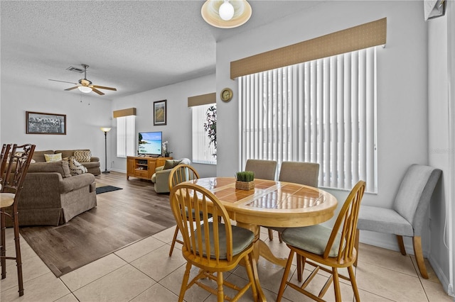 dining area featuring ceiling fan, a textured ceiling, and light wood-type flooring