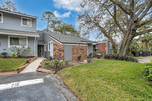 view of front of house featuring brick siding, uncovered parking, stucco siding, and a front yard