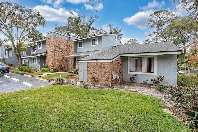 view of front of property featuring a shingled roof, a front lawn, and stucco siding