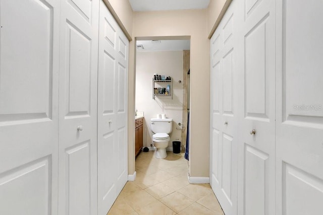 corridor featuring light tile patterned flooring and baseboards