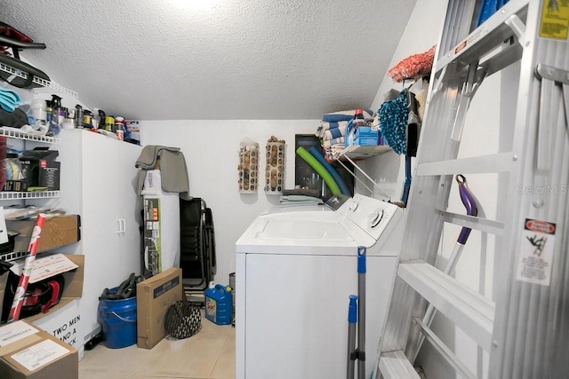 clothes washing area featuring laundry area, a textured ceiling, washing machine and clothes dryer, and tile patterned floors