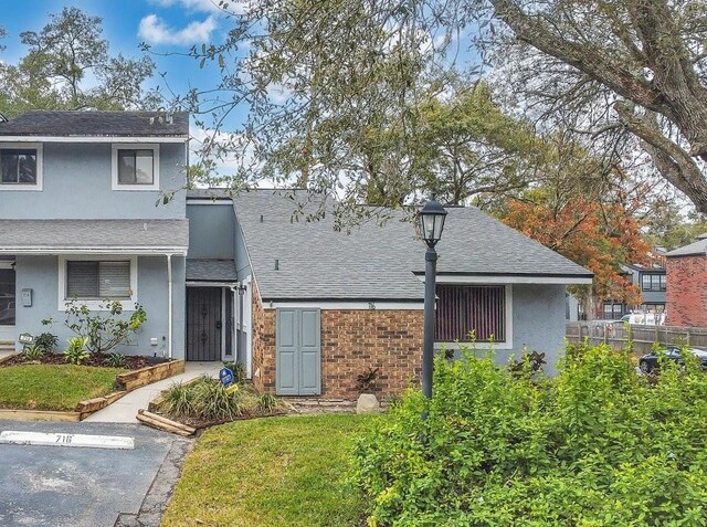 view of front of home with uncovered parking, roof with shingles, fence, and stucco siding