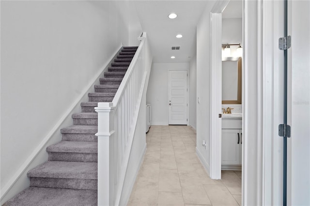 stairs featuring sink and light tile flooring