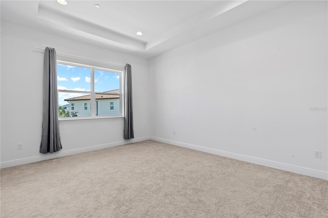 carpeted spare room with a tray ceiling